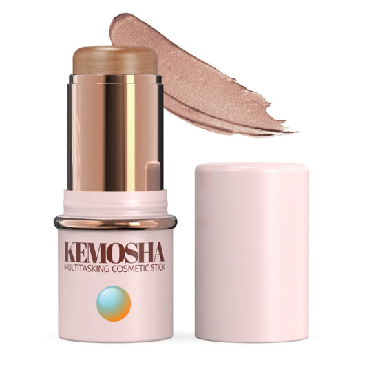 A Kemosha multitasking cosmetic stick in a light pink tube with a rose gold accent, featuring an exposed shimmery gold product and a swatch of a similar light pinkish-gold shade