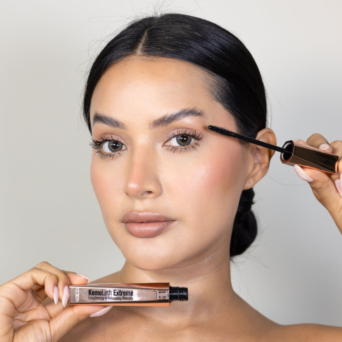 A woman applying mascara to her eyelashes
